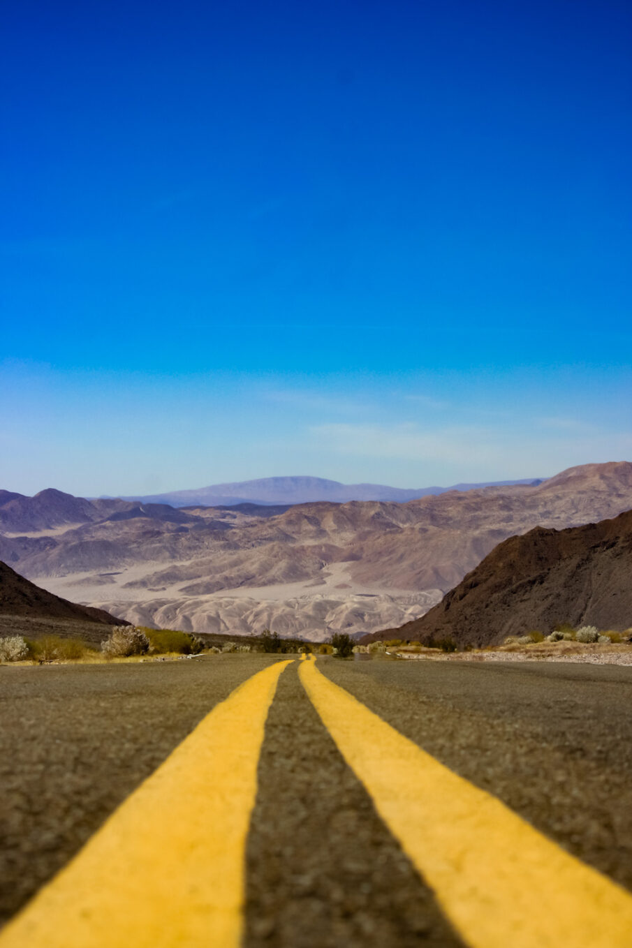 Paint lines down the center of the road with sweeping views of Death Valley National Park in the background