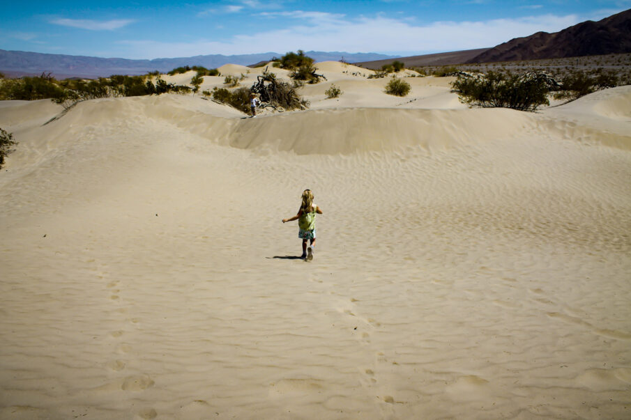 A girl runs through the desert towards the Mesquite Flat Sand Dunes in Death Valley National Park